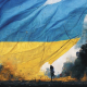 An image of the Ukrainian flag on a war field