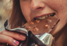 Una ragazza addenta un pezzo di cioccolato