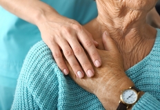 Una donna tiene la mano sulla mano di un'anziana