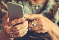 Le mani di una anziana mentre utilizza uno smartphone