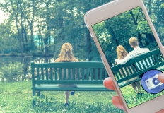 Ragazza seduta sulla panchina. Uno smartphone la inquadra e aggiunge un uomo accanto a lei falsificando l'immagine.