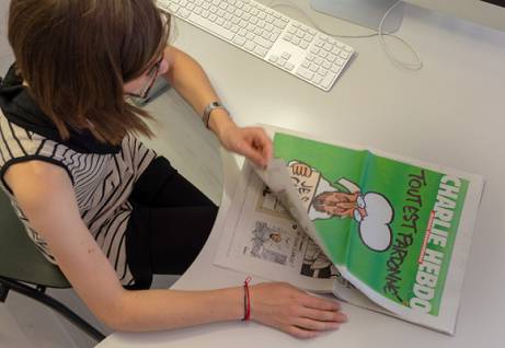 Una ragazza che sfoglia il giornale "Charlie Hebdo"