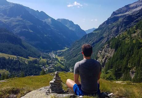 Un ragazzo seduto guarda le montagne e la valle