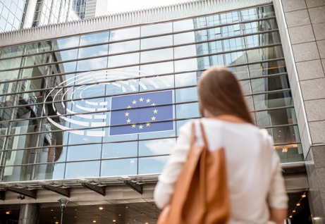 Una donna guarda la vetrata di un edificio con la bandiera europea