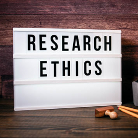 scritta "Research ethics" su una lampada da tavolo. Matite a destra