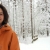 Sara Moioli con giacca arancione in un bosco innevato della Finlandia © 